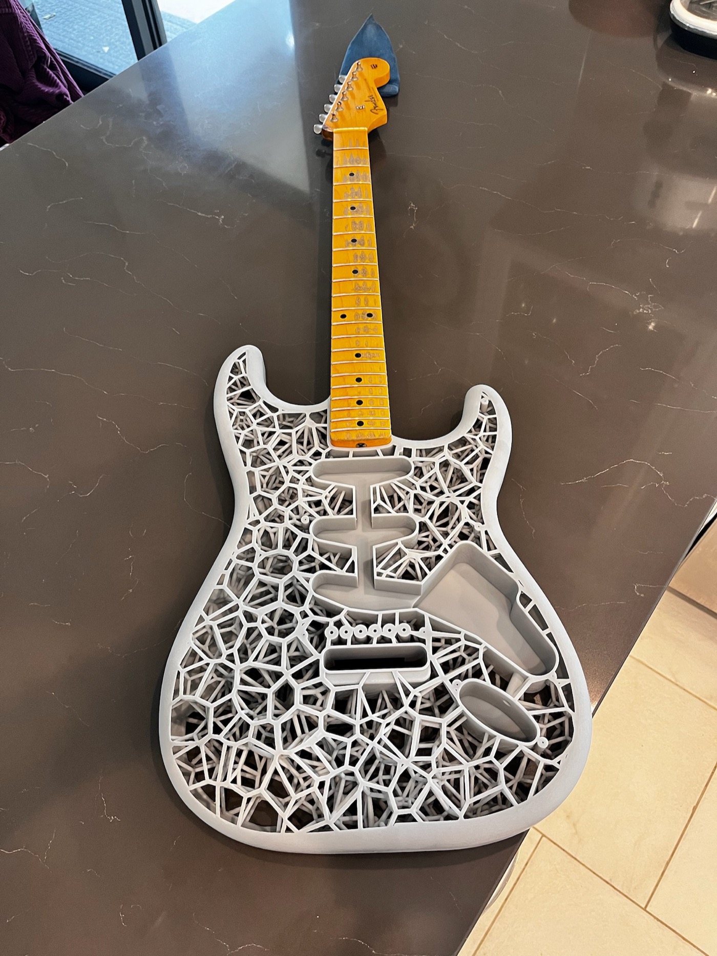Full-size resin printed Stratocaster body with Fender Clapton neck test-fitted, lying on a countertop